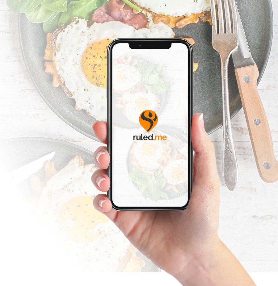 The Keto Academy open on a phone, held over a plate of fried eggs and greens