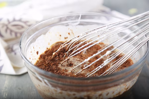 Cocoa powder and almond flour folded halfway into the brownie batter with a whisk