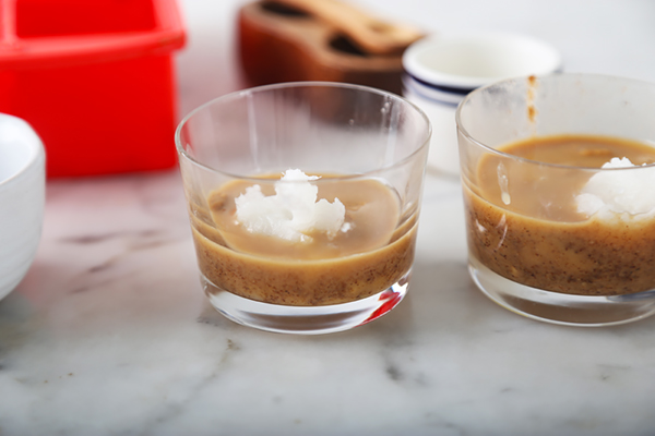 Solid coconut oil chunks placed on top of peanut butter in two glass ramekins