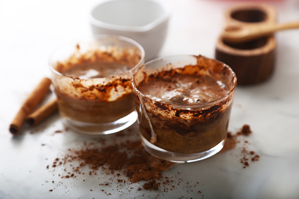 Cocoa powder stirred into peanut butter and coconut oil mixture in glass cups