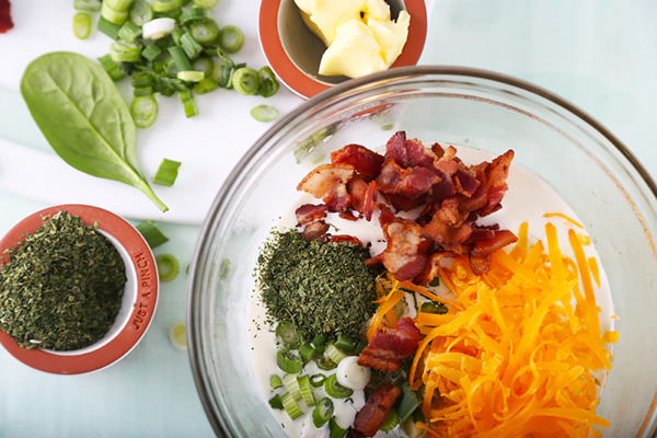 Folding chopped bacon, shredded cheddar, and dried parsley into the egg mixture