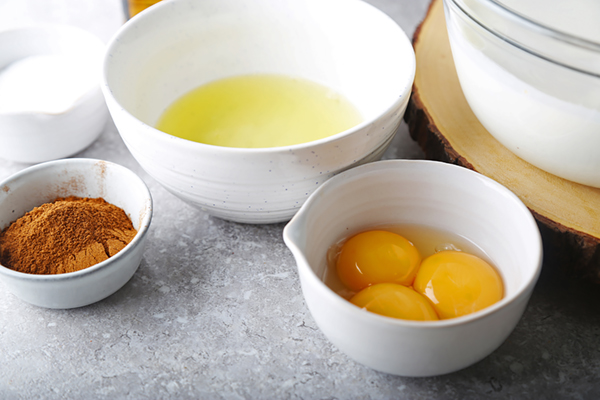 Heavy cream and coconut milk poured into a large glass bowl for eggnog