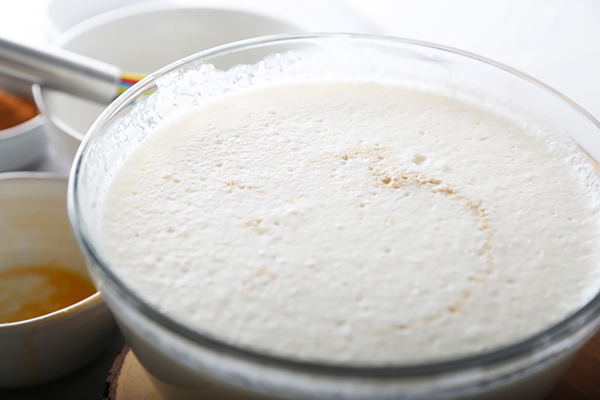Vanilla extract swirled into the frothy eggnog mixture in a glass bowl