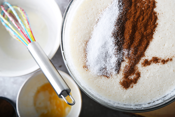 Ground cinnamon, allspice, and erythritol sweetener sprinkled over the eggnog mixture