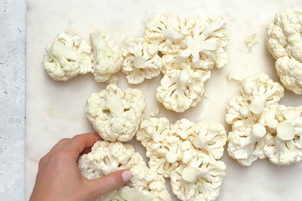 Cauliflower florets cut and spread across a white surface