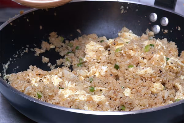Scrambled egg pieces mixed into seasoned cauliflower fried rice with green onions