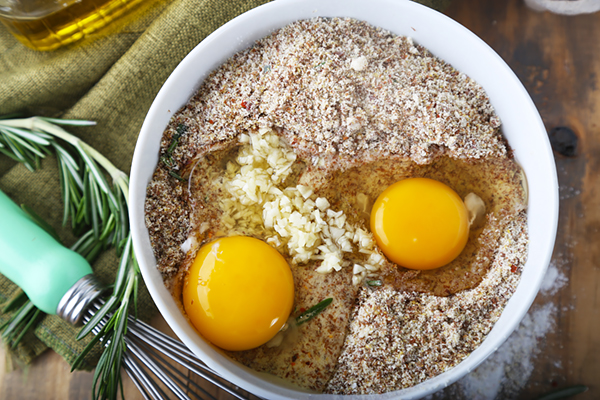 Two cracked eggs with minced garlic in the focaccia dry ingredients bowl