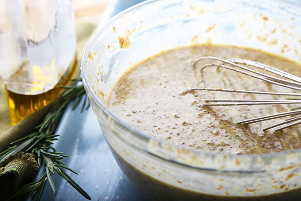 Whisking focaccia batter with olive oil until smooth and aerated in a glass bowl