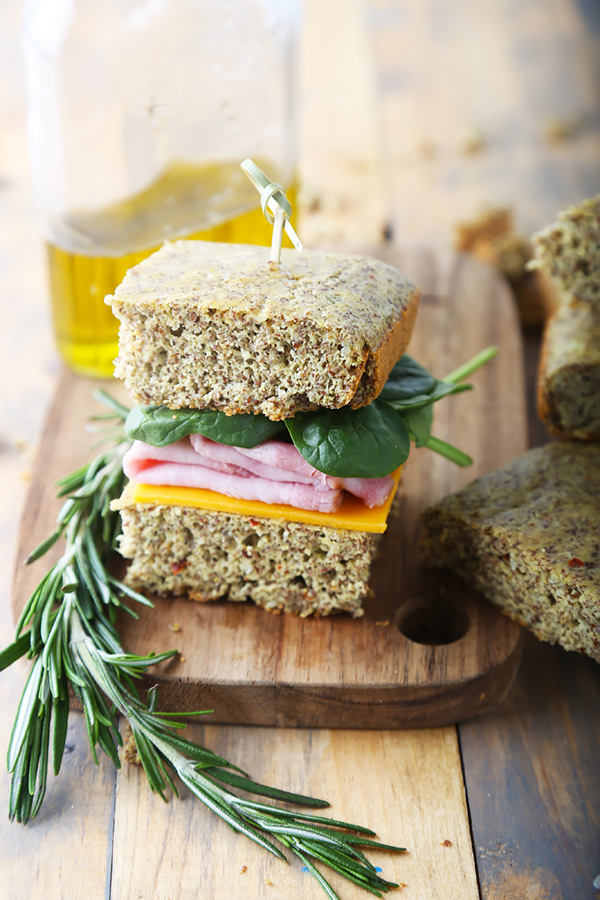 Focaccia sandwich stacked with ham, cheddar, and spinach on a wooden board