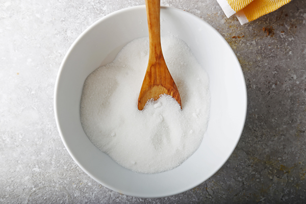 Powdered erythritol in a white bowl with a wooden spoon for cupcake icing