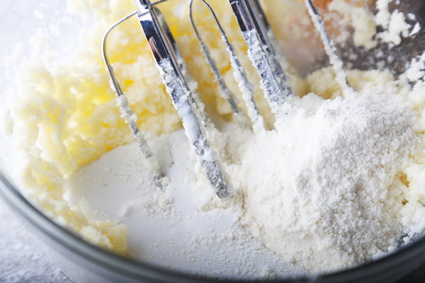 Hand mixer blending coconut milk into the butter and erythritol icing