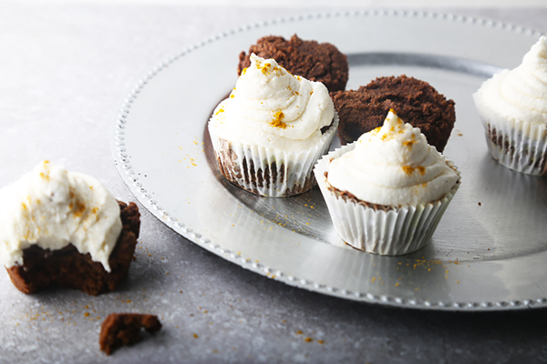 Chocolate curry cupcakes topped with swirled white buttercream and curry powder on a silver tray