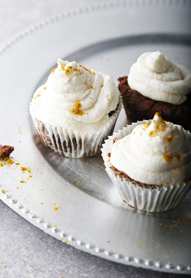 Three frosted chocolate curry cupcakes dusted with curry powder on a silver serving tray