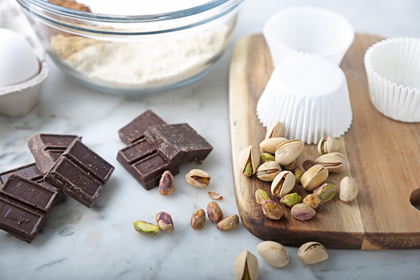 Dark chocolate squares, shelled pistachios, eggs, and almond flour laid out for pumpkin muffins