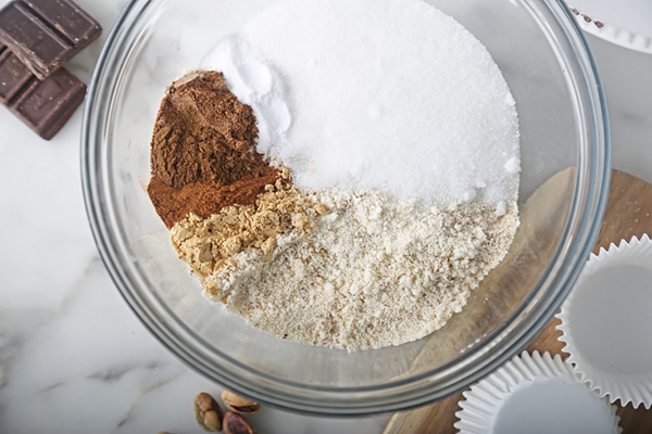 Almond flour, erythritol, ground cinnamon, and baking soda measured into a glass mixing bowl