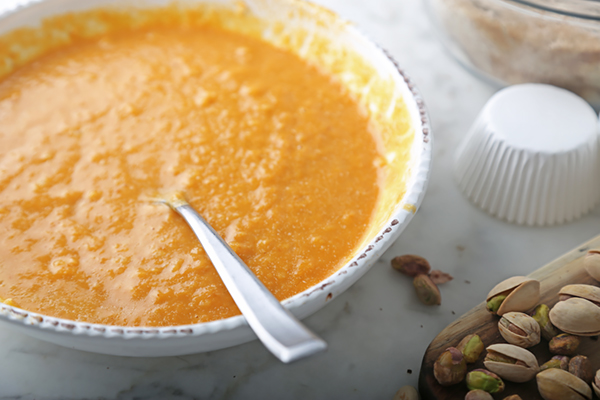 Whisked pumpkin puree, egg, and coconut oil mixture smooth and orange in a white bowl