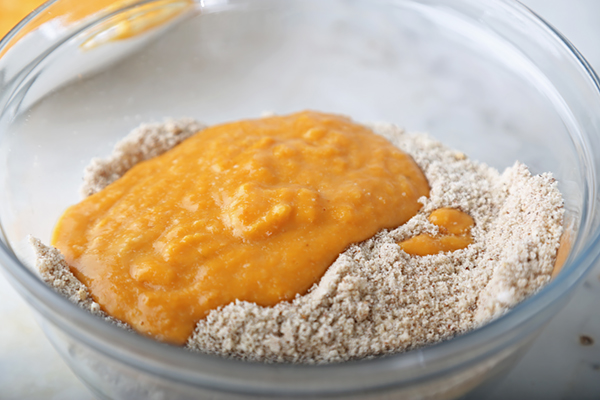 Pumpkin wet mixture poured over the almond flour dry ingredients in a glass bowl