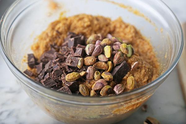 Folding dark chocolate chunks and pistachios into thick pumpkin muffin batter