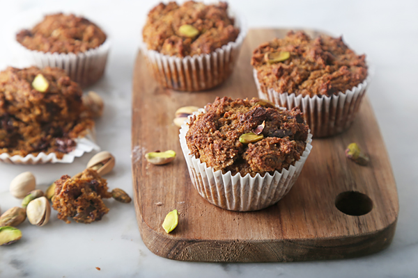 Golden baked chocolate pistachio pumpkin muffins cooling on a wooden board