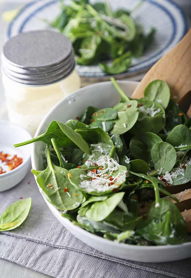 Tossed spinach salad with ranch dressing, parmesan, and red pepper flakes served with wooden spoons