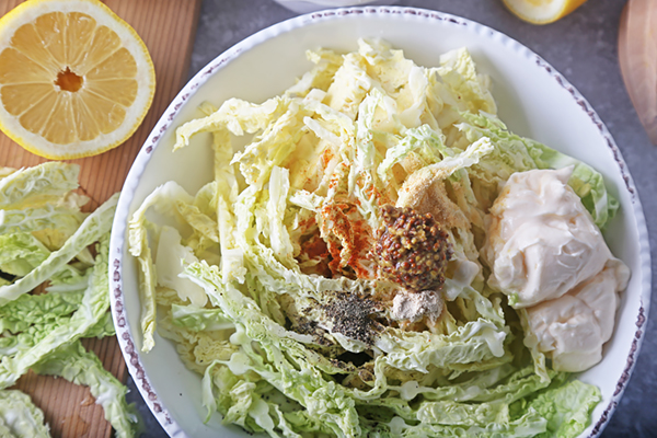 Shredded cabbage in a bowl with mayonnaise, Dijon mustard, paprika, and black pepper
