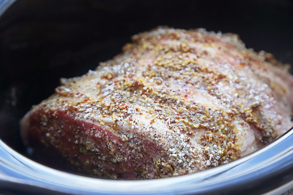 Lamb leg rubbed with whole grain mustard, olive oil, salt, and pepper in a slow cooker