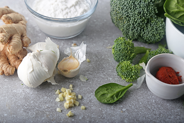 Fresh ginger, garlic, broccoli, spinach, coconut cream, and red curry paste laid out