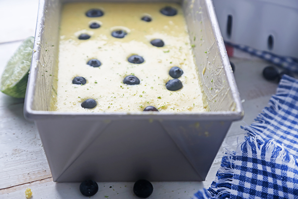 Baked blueberry lime cake with flecks of lime zest cooling in a loaf pan