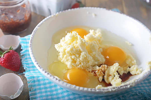 Eggs, vanilla extract, and creamed butter together in a white bowl