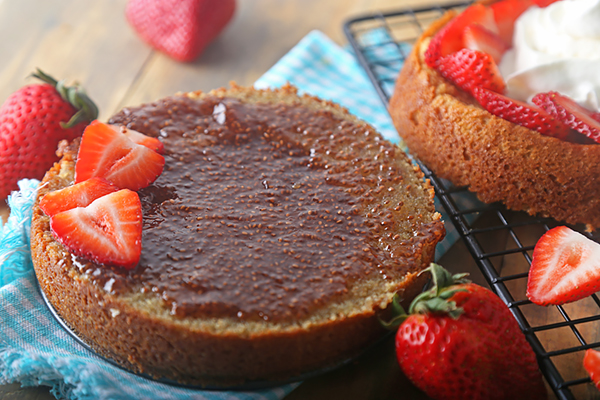 Two baked shortcake layers spread with strawberry chia seed jam and sliced strawberries