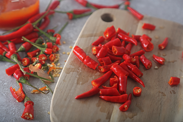 Chopped bird's eye chile peppers with seeds removed on a wooden cutting board