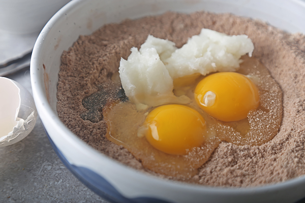 Eggs, coconut oil, and vanilla extract added to the gingerbread dry ingredients