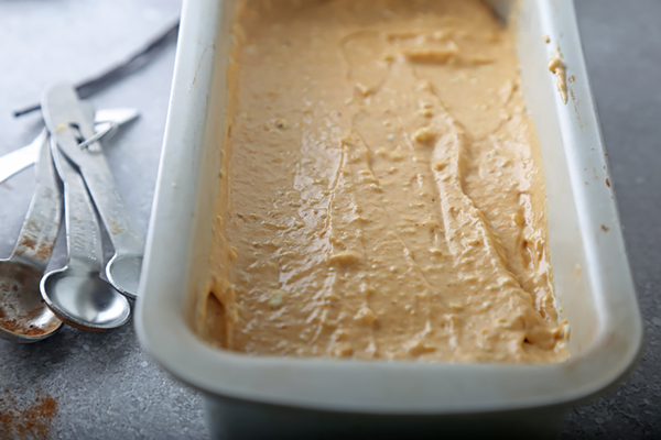 Smooth pumpkin cheesecake filling spread over the gingerbread crust in a loaf pan
