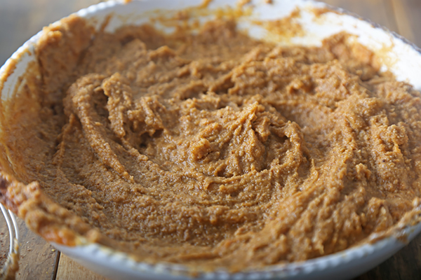 Thick pumpkin spice muffin batter stirred together in a white bowl