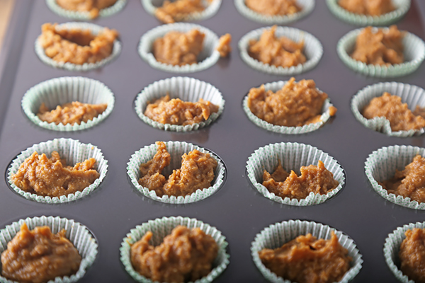 Pumpkin spice batter scooped into paper-lined mini muffin pan wells