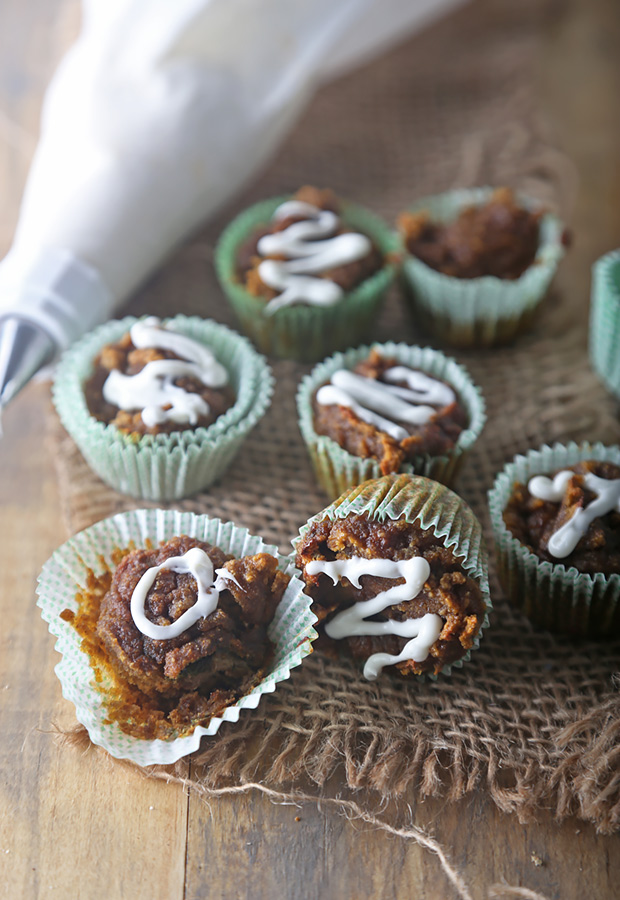 Mini pumpkin spice muffins drizzled with cream cheese icing on a rustic table