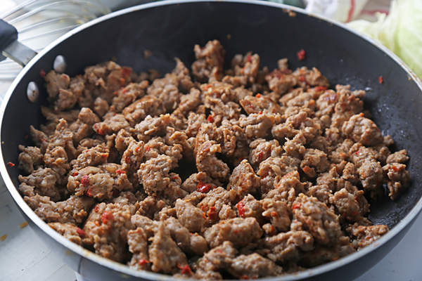 Browning pork sausage with red pepper flakes in a large skillet