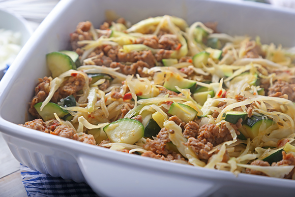 Sausage, cabbage, and zucchini filling layered in a white casserole dish