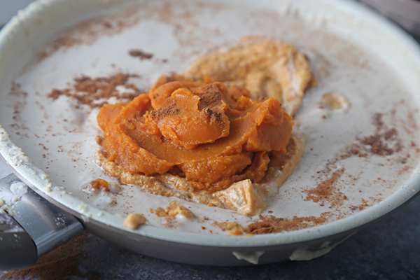Pumpkin puree and ground cinnamon added to the melted coconut butter in the pan