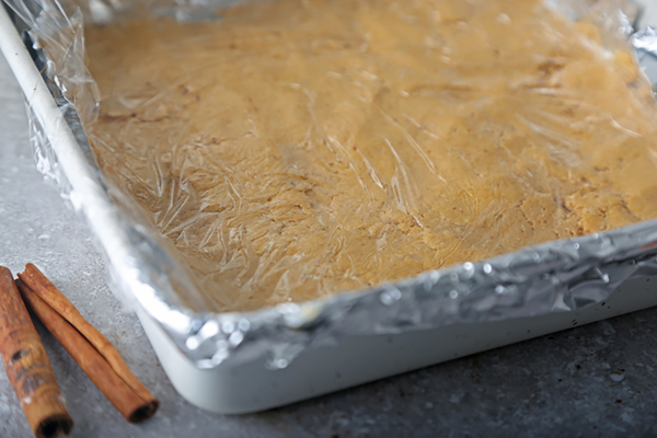 Wax paper pressed flat over the pumpkin fudge to smooth the surface