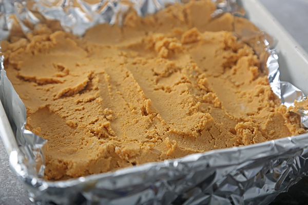 Chilled pumpkin fudge block lifted from the pan on its foil lining