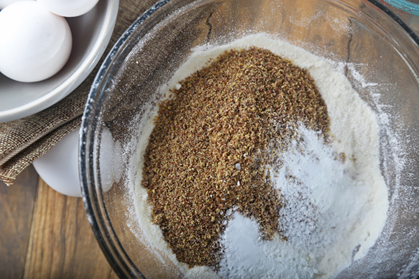 Flaxseed meal added to sifted coconut flour in a glass bowl