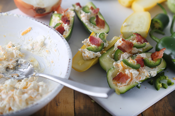 Zucchini boats filled with cream cheese mixture and topped with crumbled bacon and jalapeno