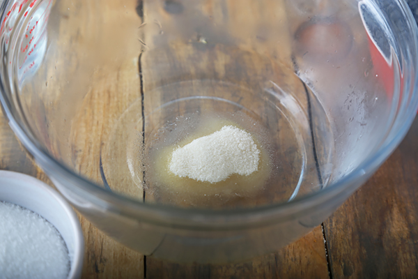 Unflavored gelatin dissolving in hot water inside a glass mixing bowl