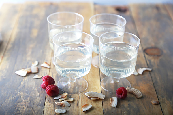 Rum gelatin mixture poured into small plastic cups on a wooden table