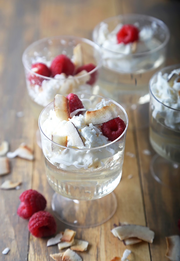 Keto rum jello shots topped with whipped cream, raspberries, and toasted coconut flakes