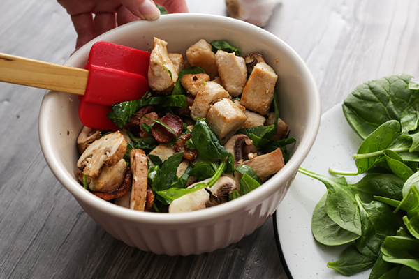 Mixing chicken and mushrooms together.