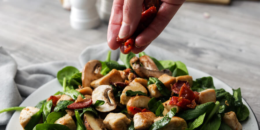 Sprinkling tomatoes on the salad.