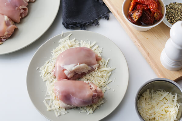 Chicken being breaded with cheese.