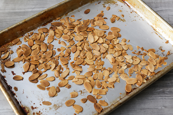 Browned almonds spread out on a baking sheet.
